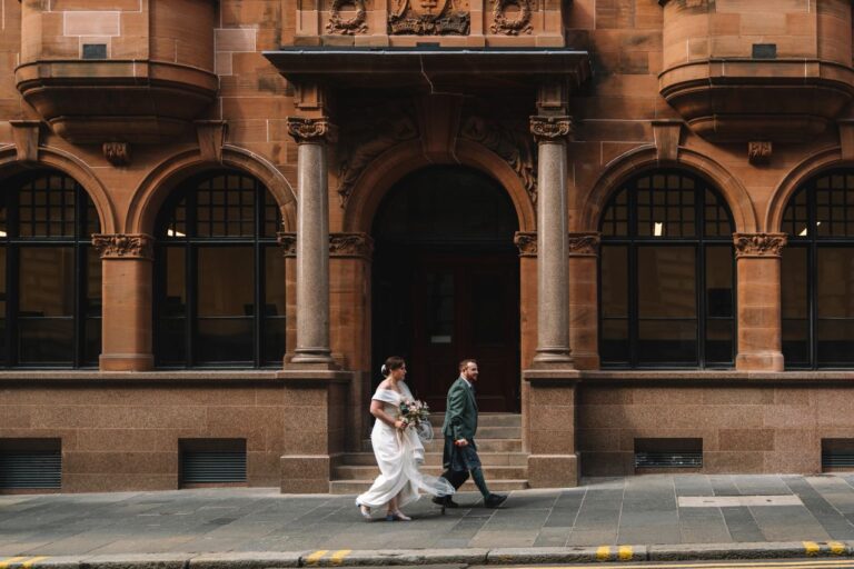 Bride and groom walking past historic Edinburgh building
