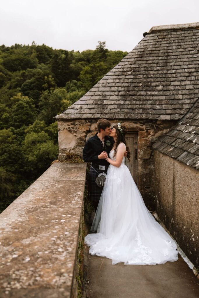 bride and groom stand on rooftop at Neidpath Castle