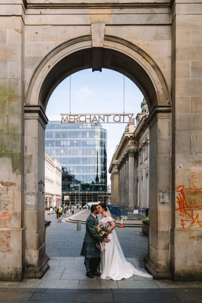 Couple embracing under stone archway in Edinburgh