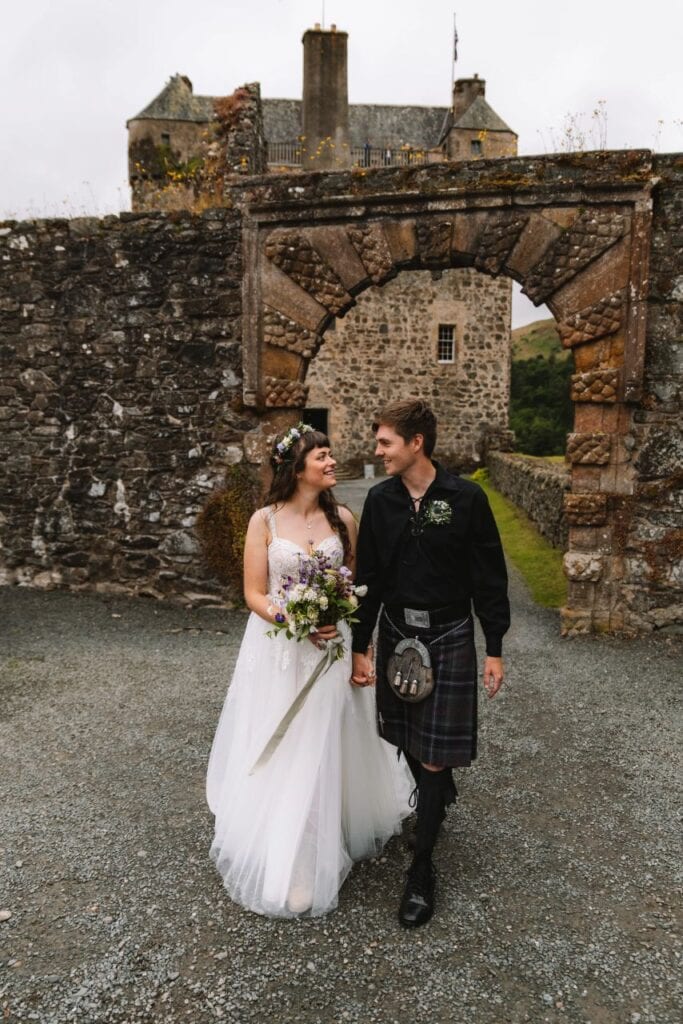 bride and groom walk through Neidpath Castle grounds