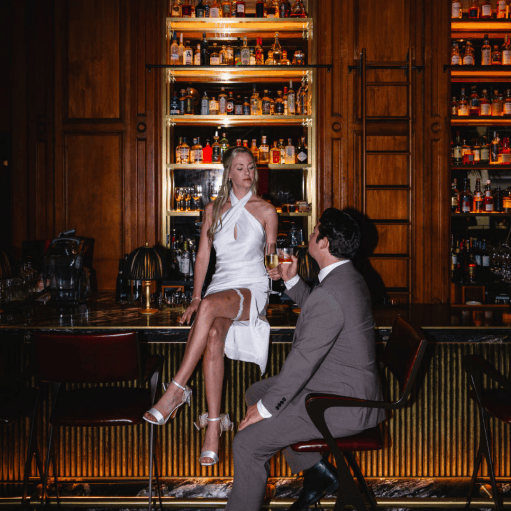 Bride sitting on bar counter with groom beside her