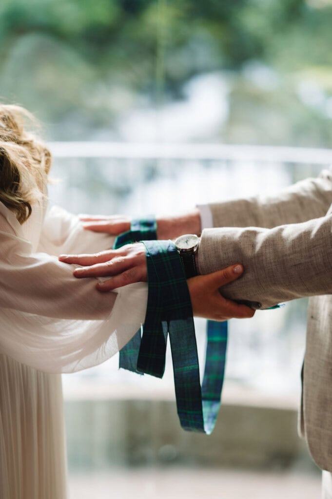 Close-up of hands tied with traditional handfasting ribbon