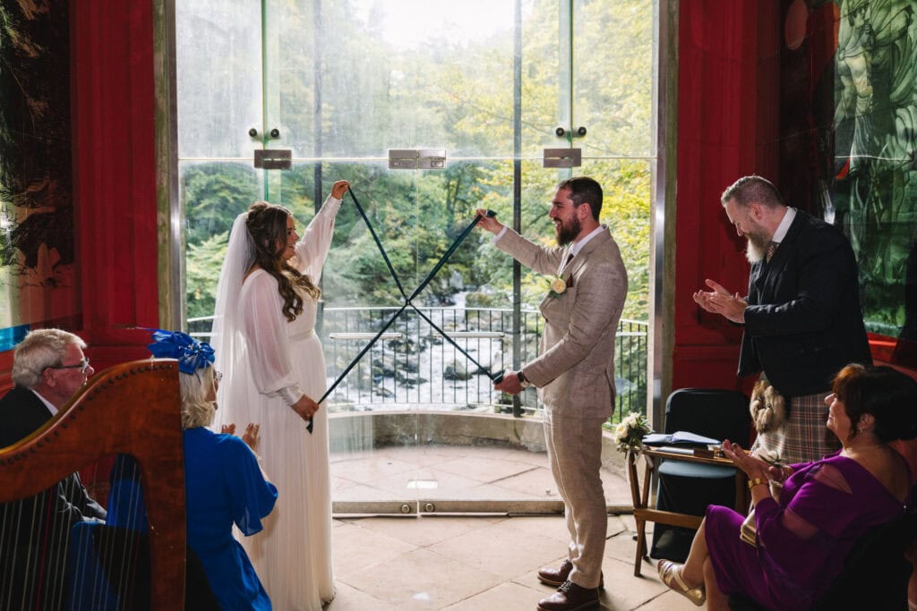Handfasting ceremony inside glass-walled venue