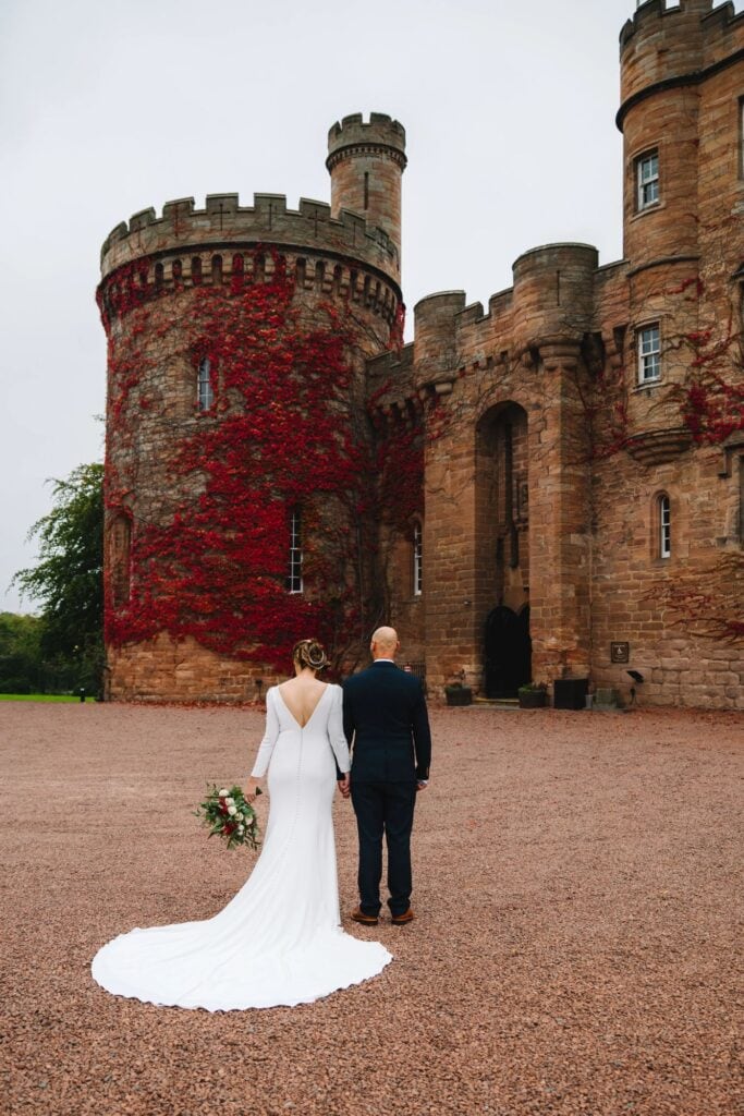  Bride and groom walking away from castle entrance