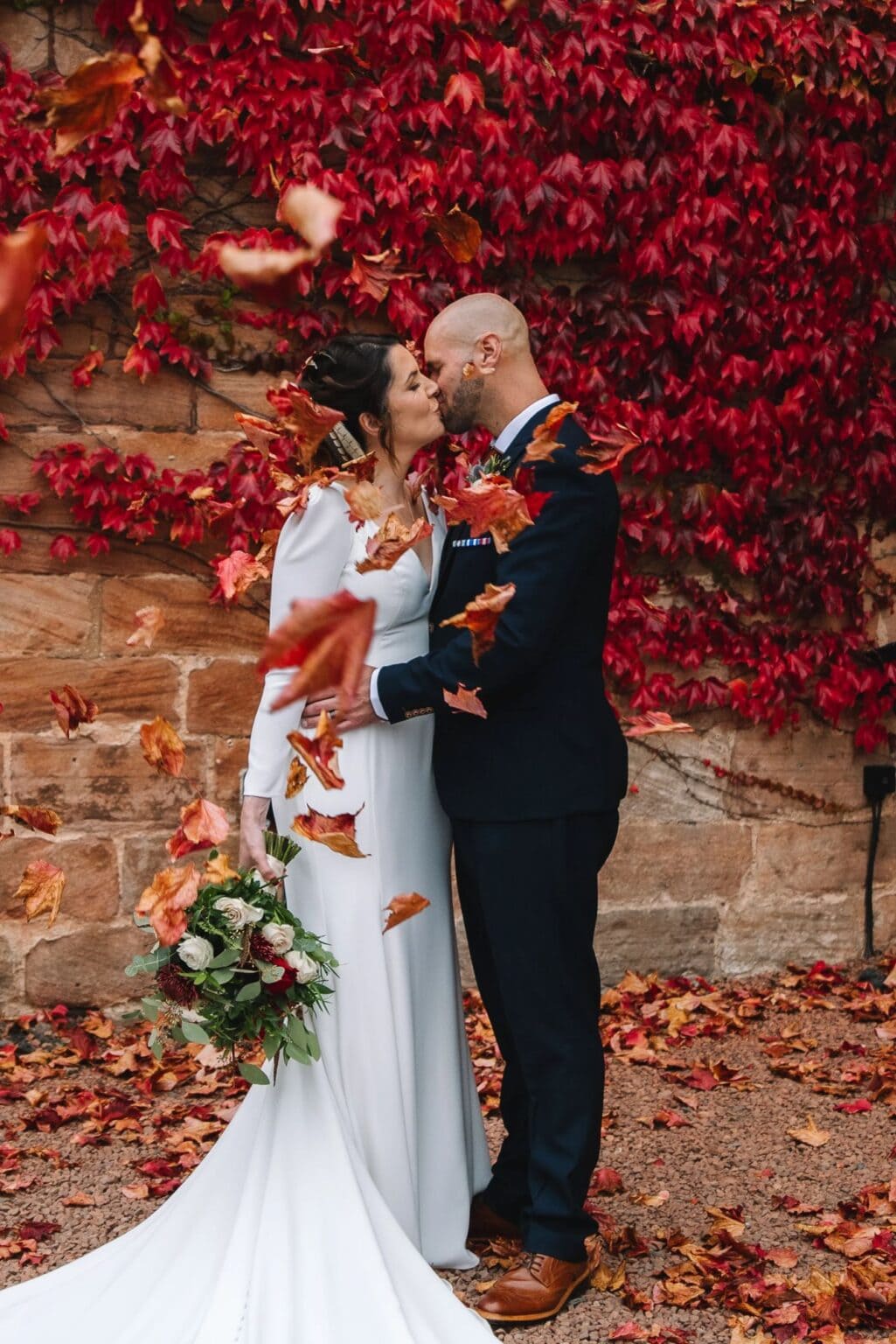 
Couple embracing against red ivy wall at castle venue