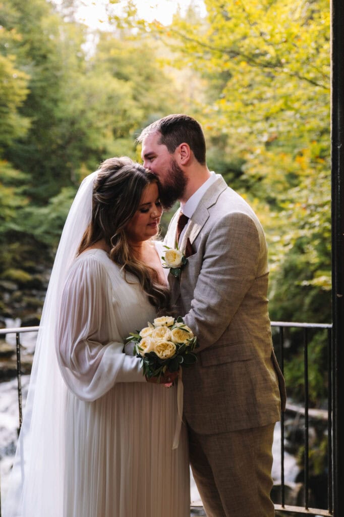 Couple embracing on balcony overlooking forest waterfall