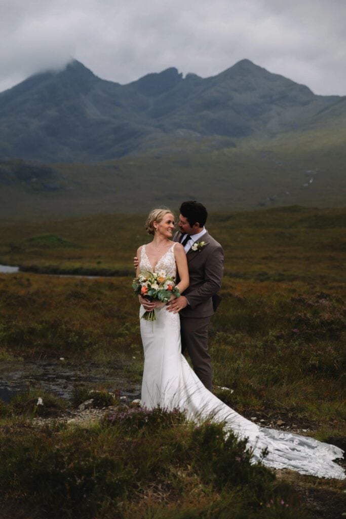 Bride and groom embracing in mountainous landscape