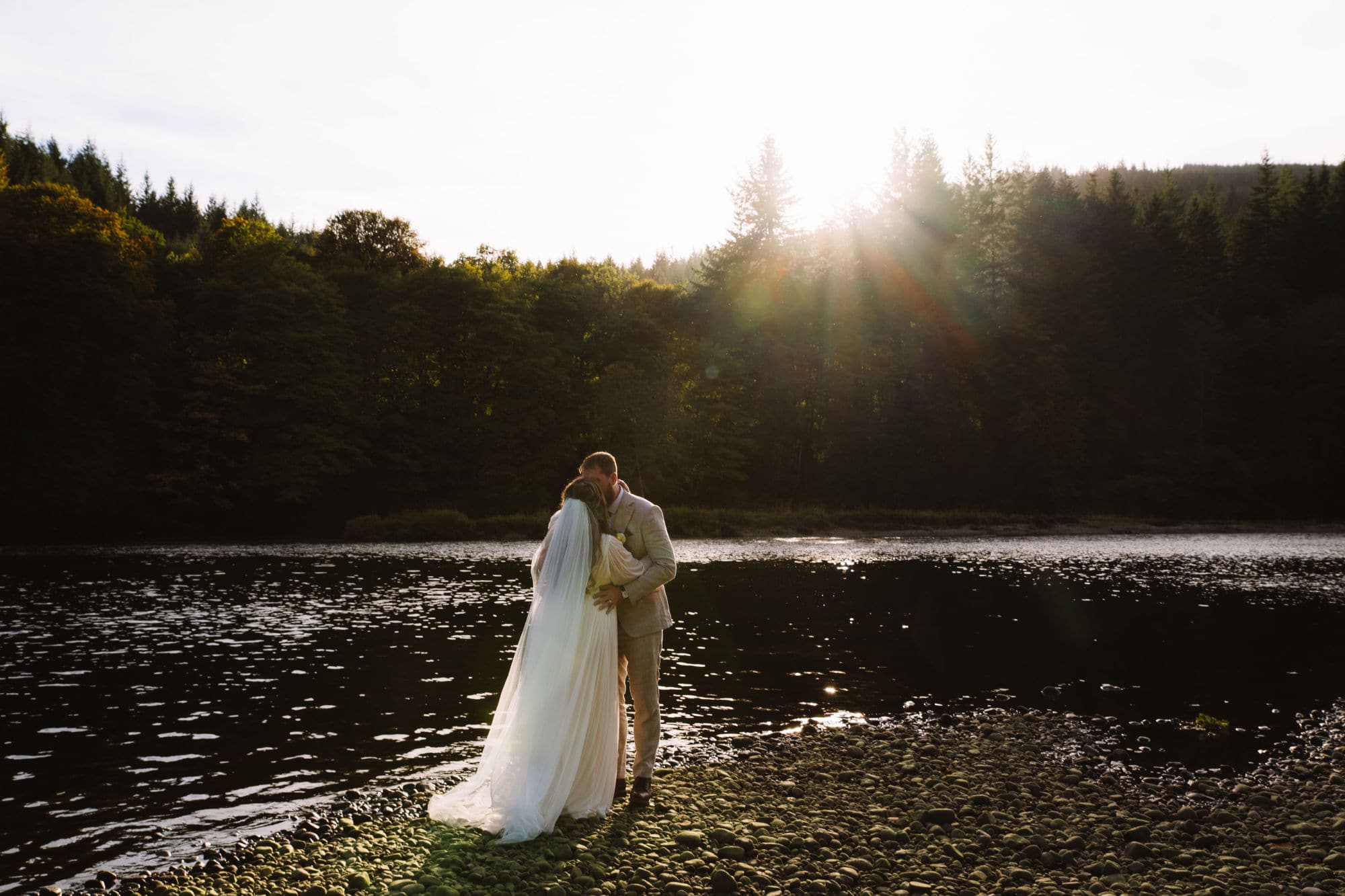 Couple embracing by river at sunset in Scotland
