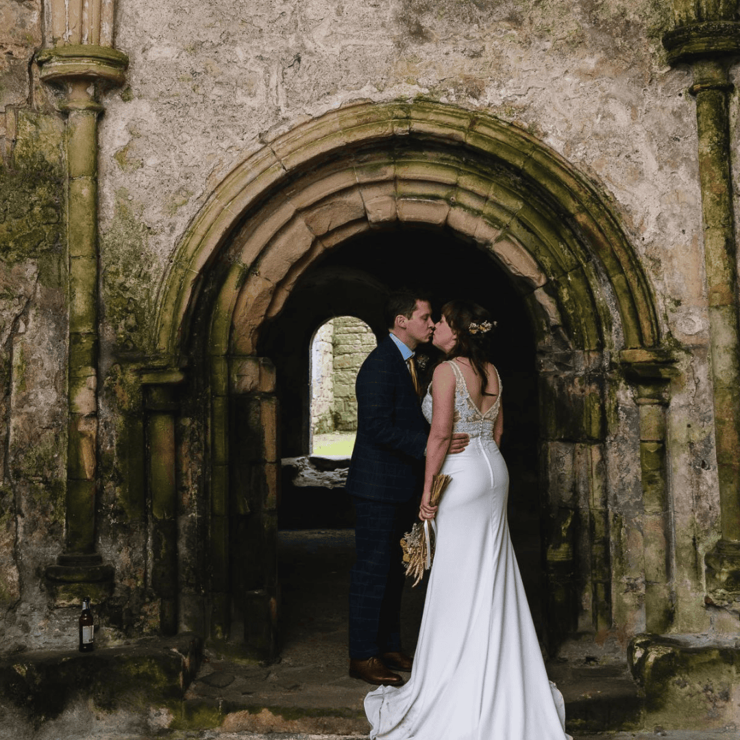 Couple kissing under stone archway at historic Scottish venue
