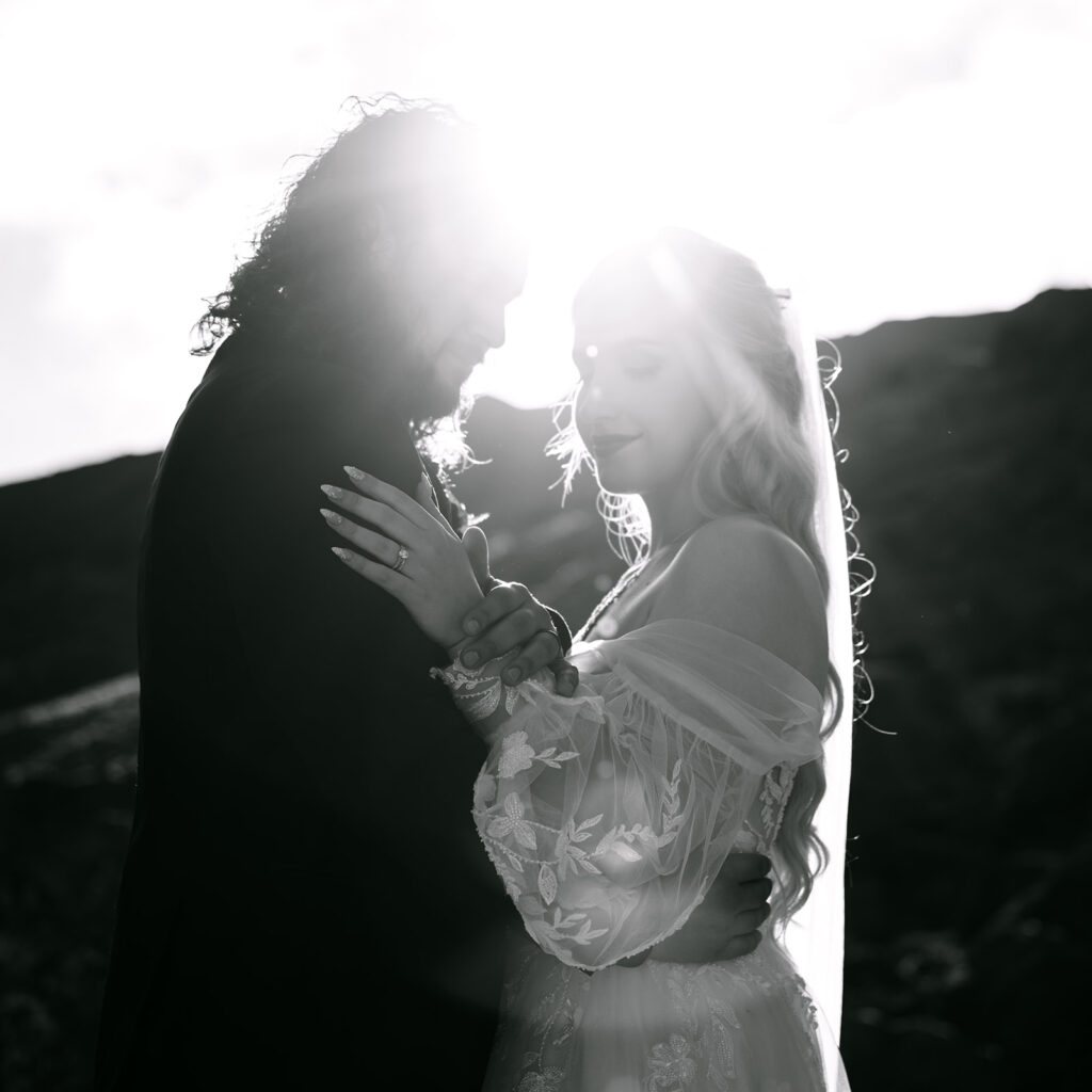 Couple embracing in backlit silhouette during romantic moment.