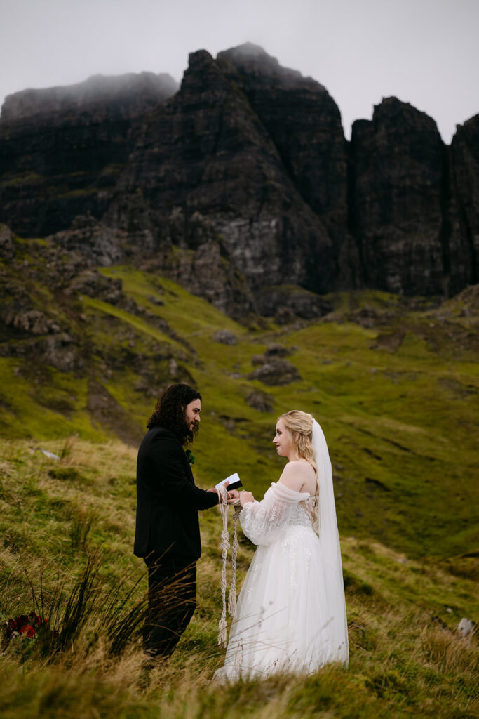 Couple exchanging vows in dramatic mountainous landscape.