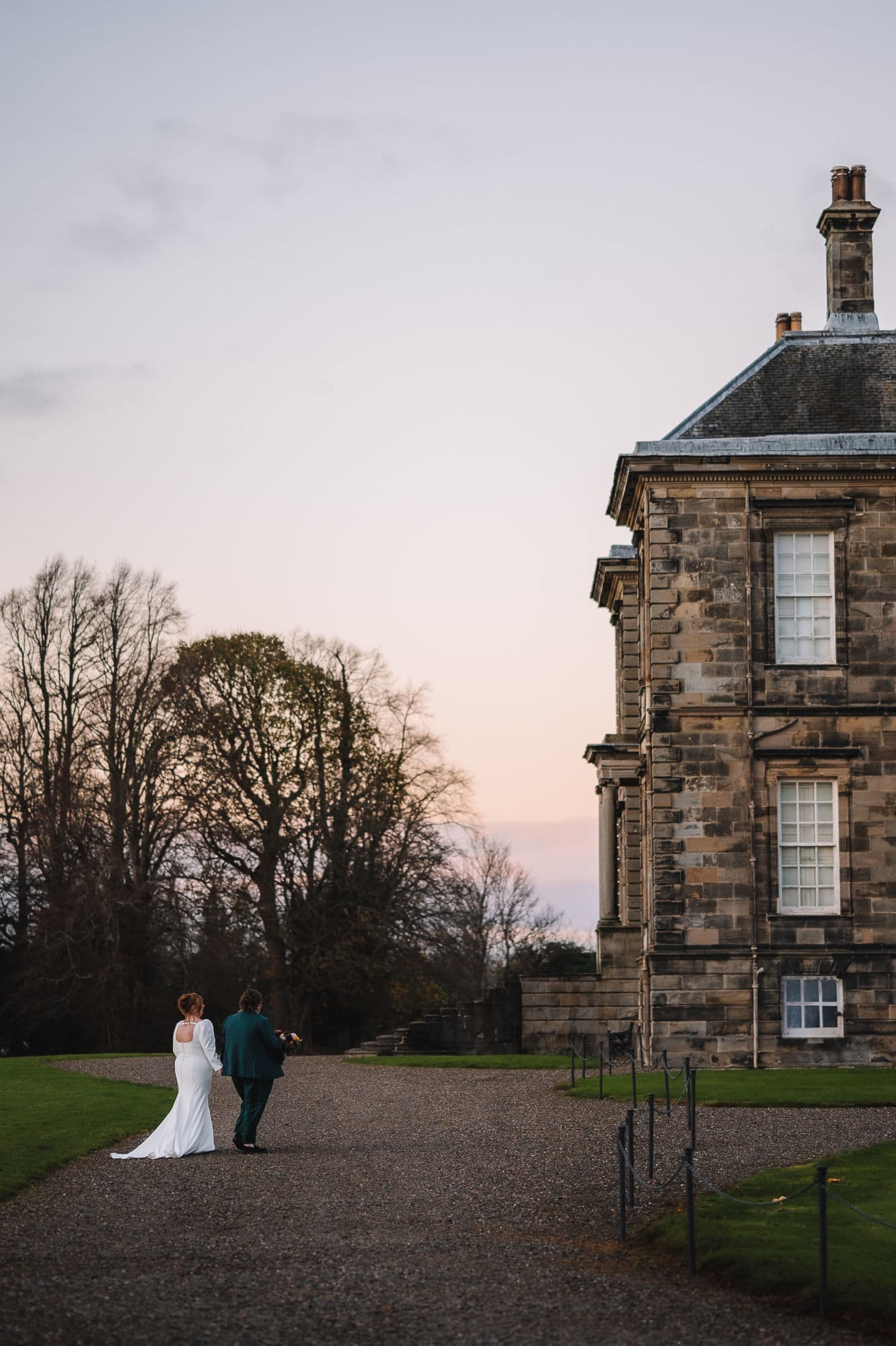 Bride standing beside groom in front of country estate