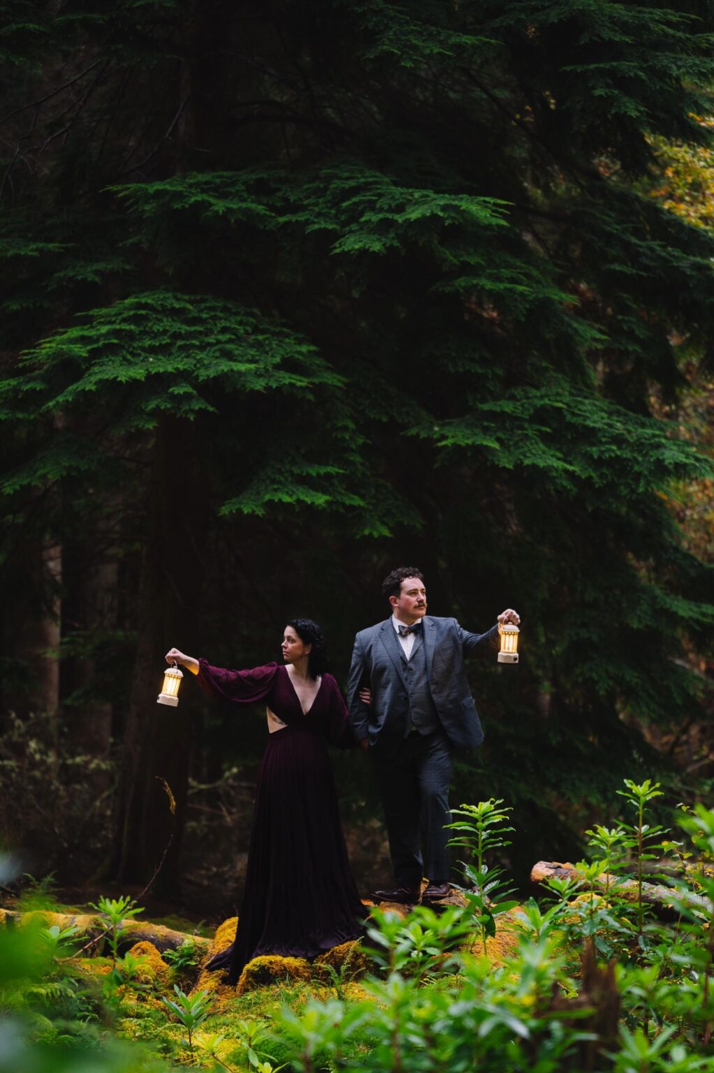 Couple walking through forest holding lanterns in Scotland