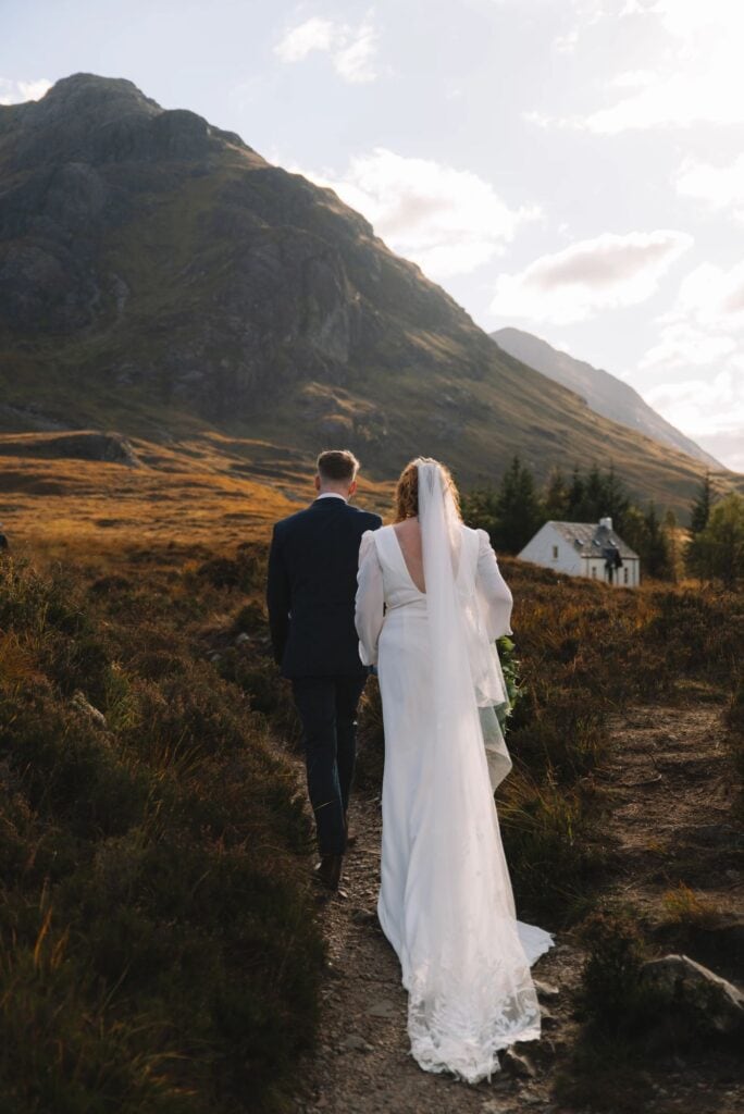 Bride and groom walking across rocky terrain outdoors