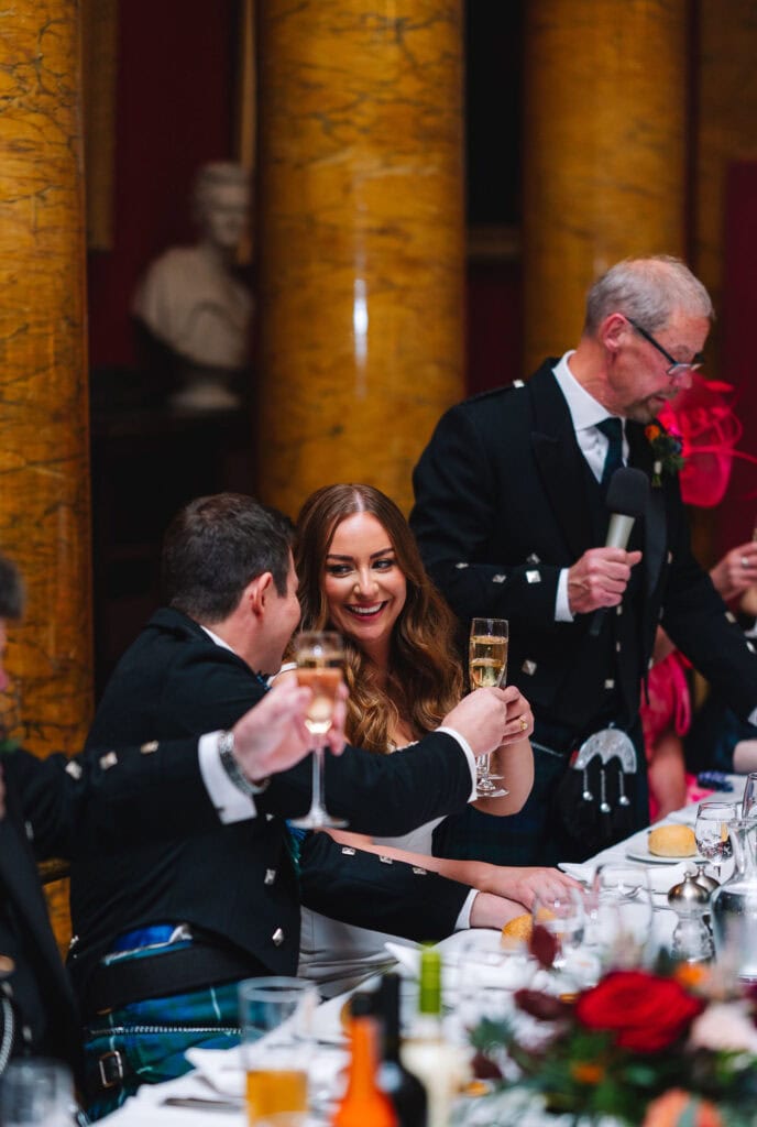 Couple laughing and toasting drinks at wedding reception
