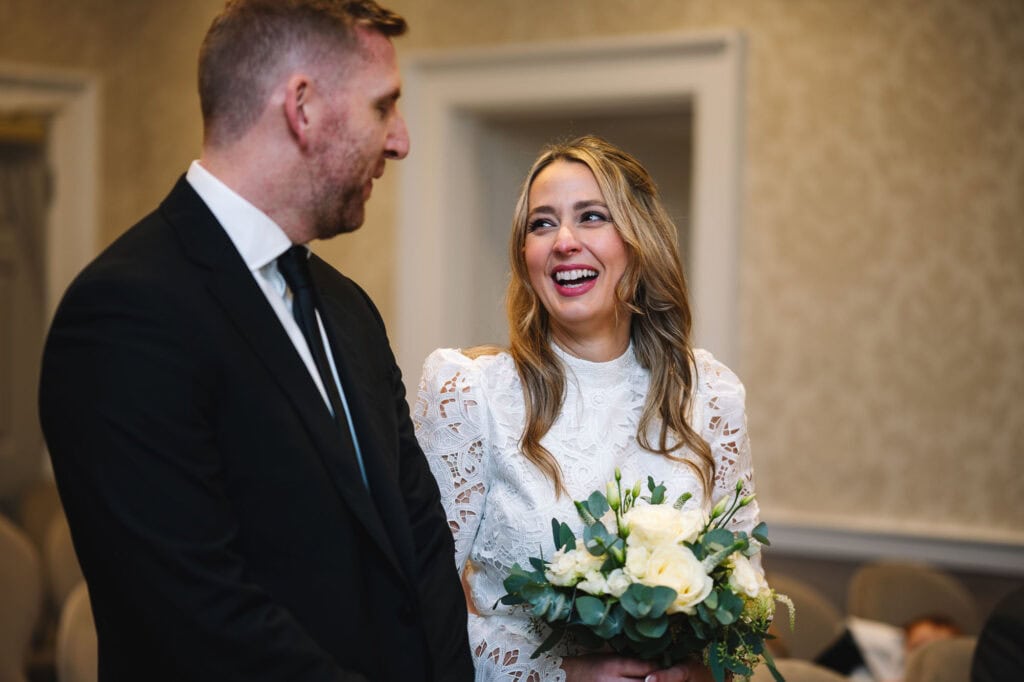 Couple smiling during ceremony moment indoors.