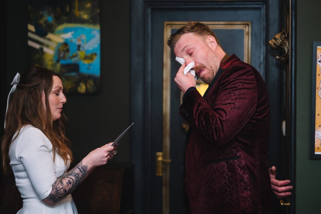 Groom reacting emotionally during candid moment indoors.