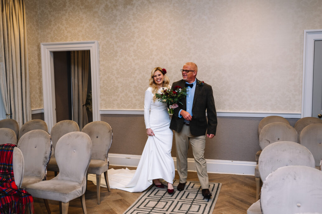 Bride walking down aisle with father at indoor ceremony