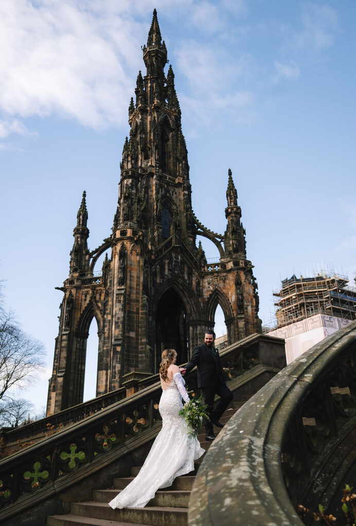 Couple standing near tall Gothic monument in city.