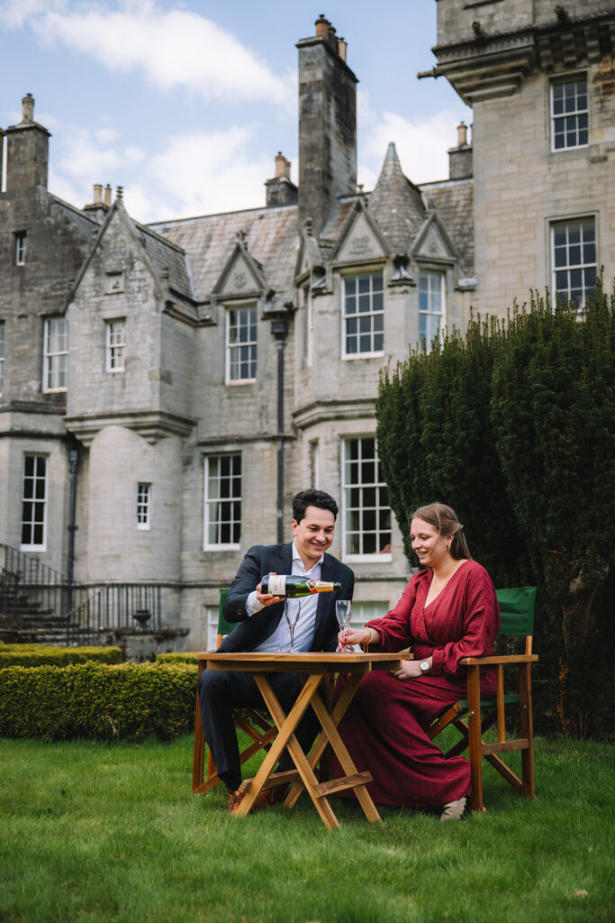 Couple sitting at table outdoors near castle facade.