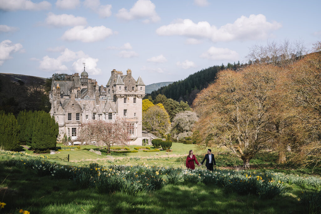 Wide view of castle estate with trees and rolling landscape.