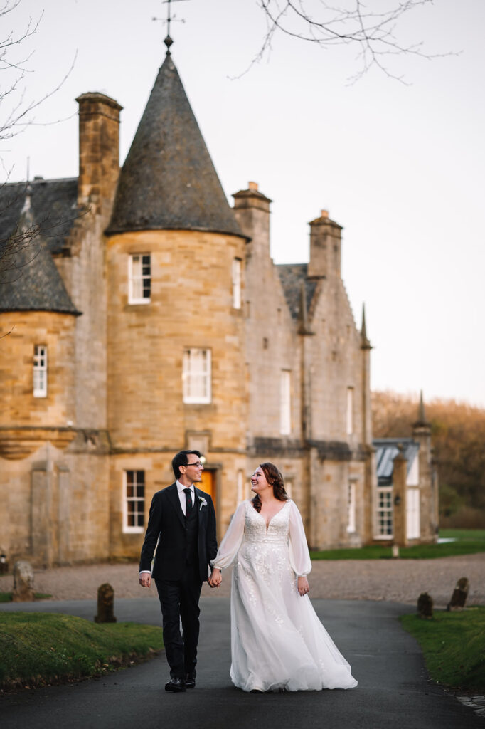 Couple walking together in front of castle building.