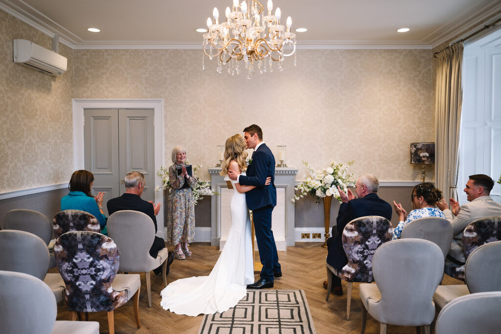 Indoor ceremony with guests seated in elegant room.