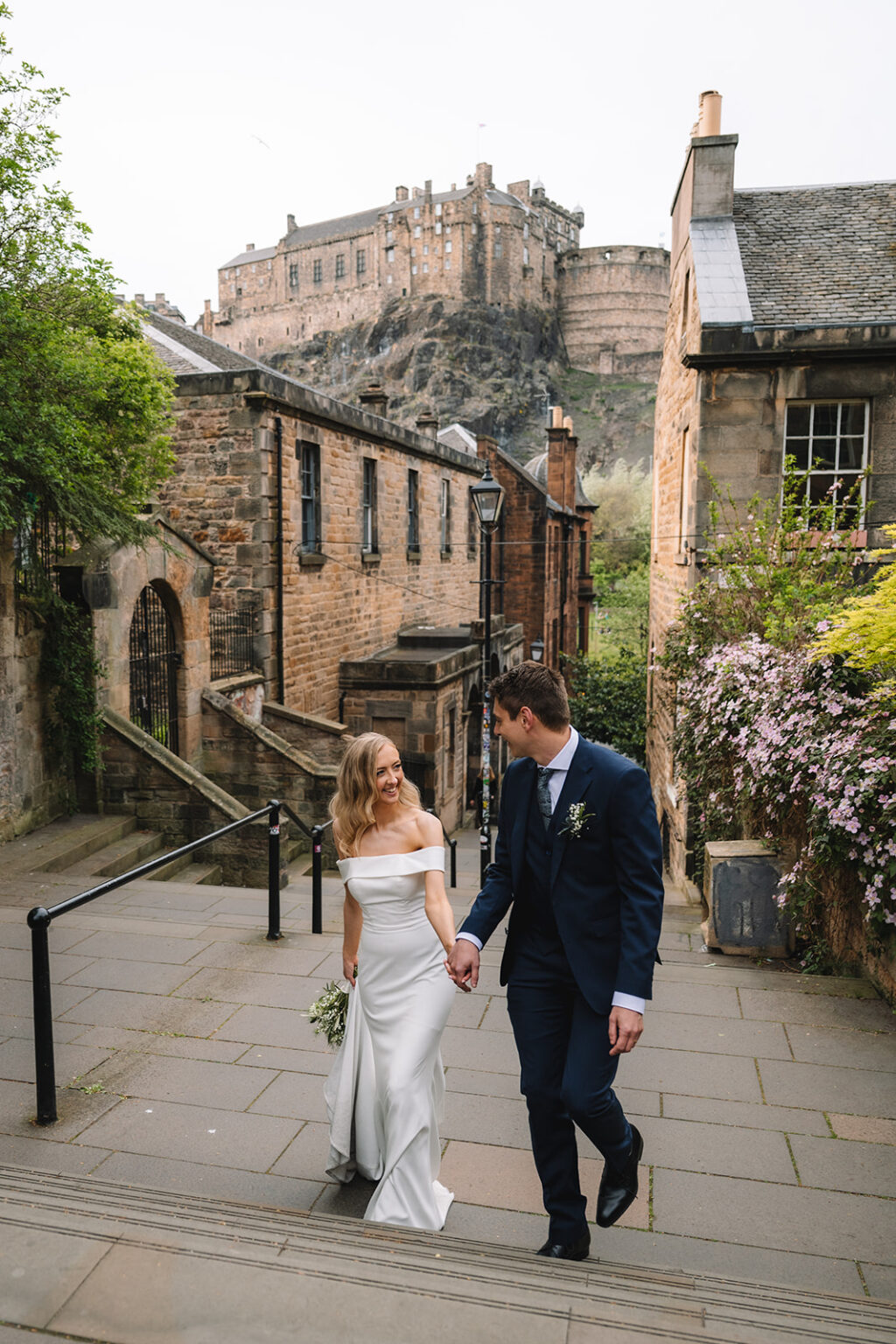 Couple walking together along stone street near old buildings.
