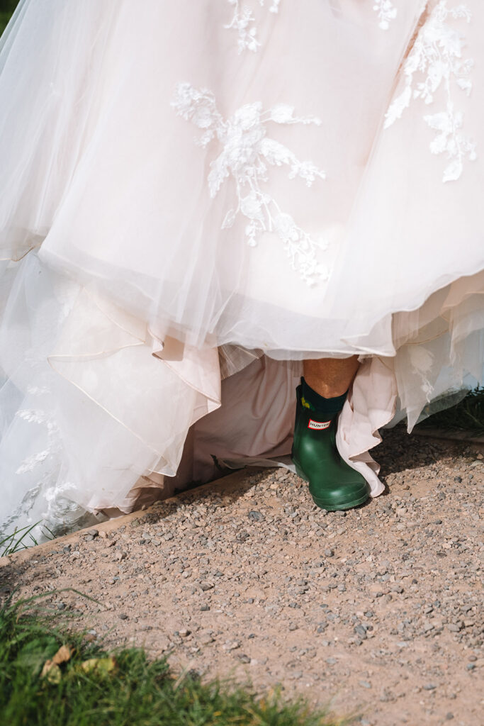 bride lifts dress revealing wellies close up details
