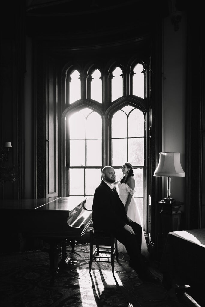 Couple silhouetted by large window in elegant interior.