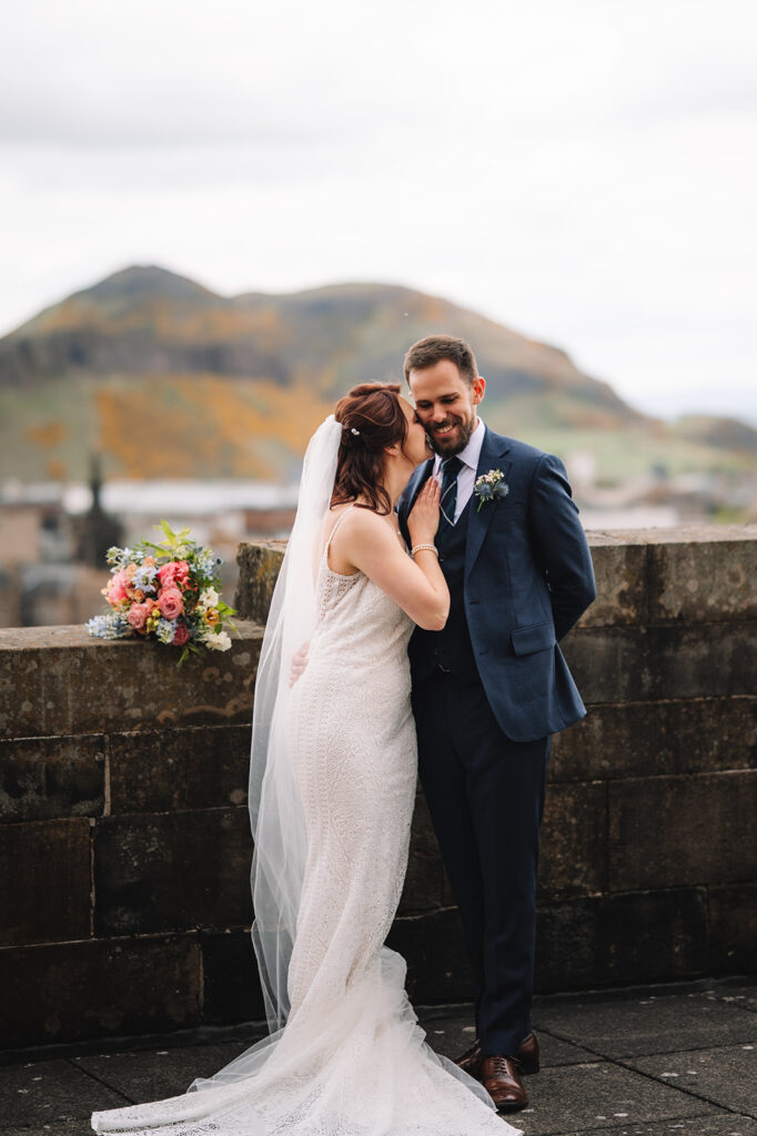 Couple embracing on stone terrace with scenic backdrop.