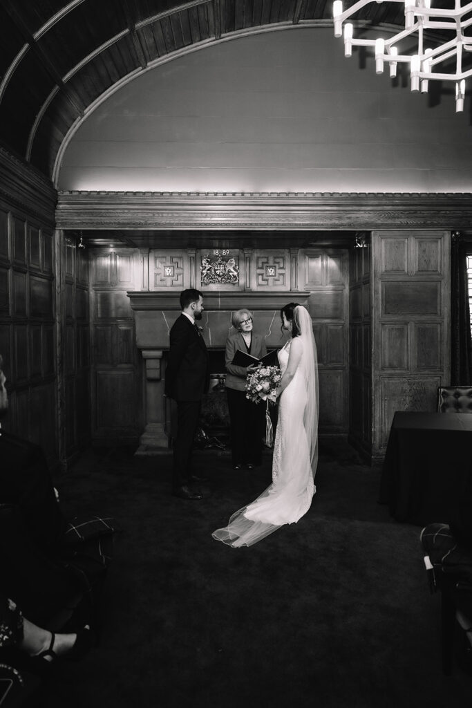 Couple standing together in dimly lit wood-paneled room.