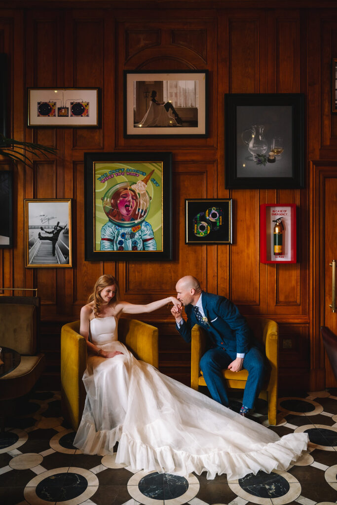Couple seated in stylish bar interior with colorful artwork backdrop.