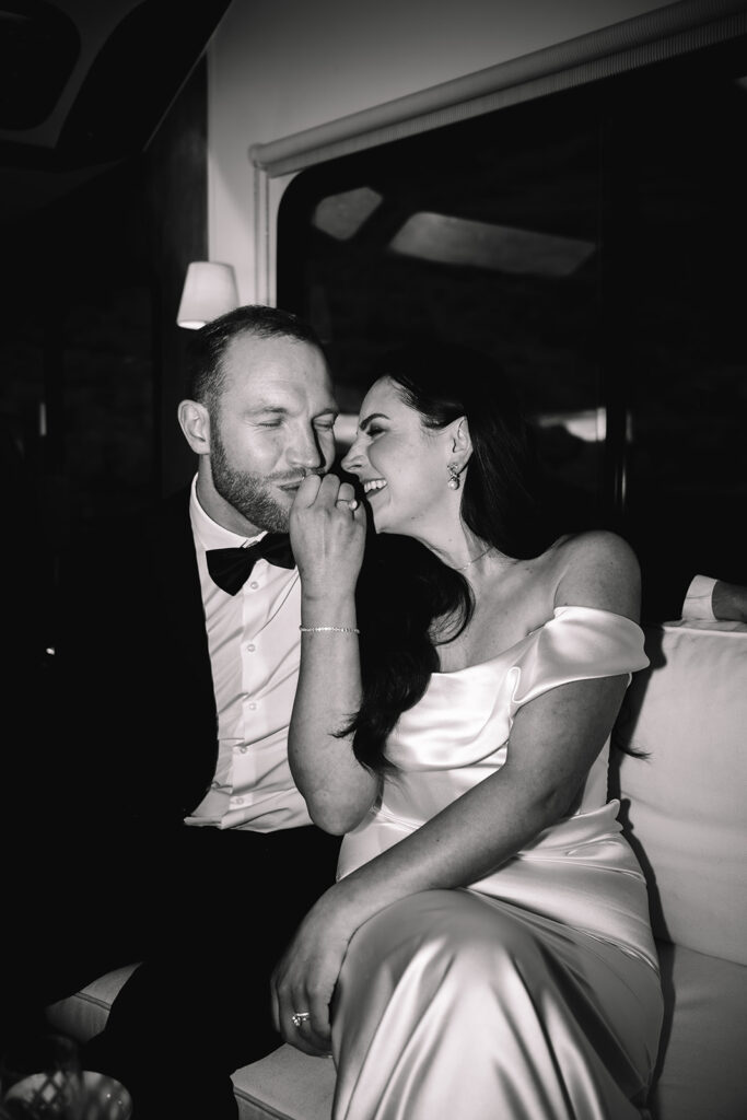 Black and white portrait of couple kissing inside vehicle.