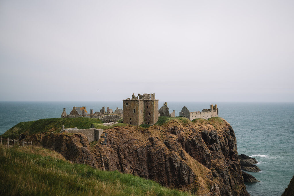 Clifftop castle ruins overlooking ocean with dramatic coastal view.