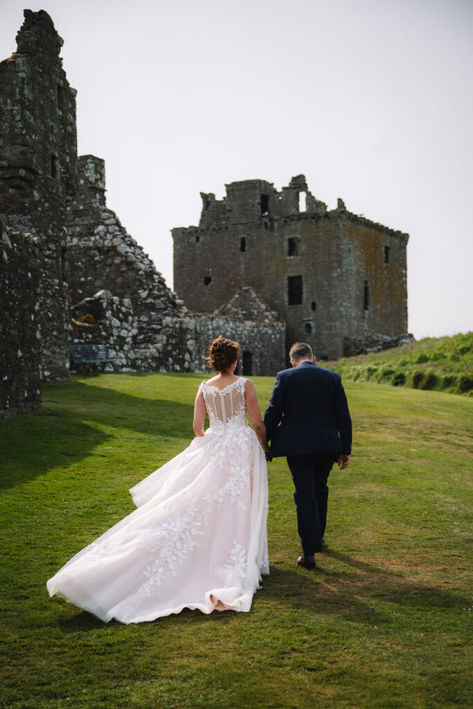 bride and groom walk away at Dunnottar Castle