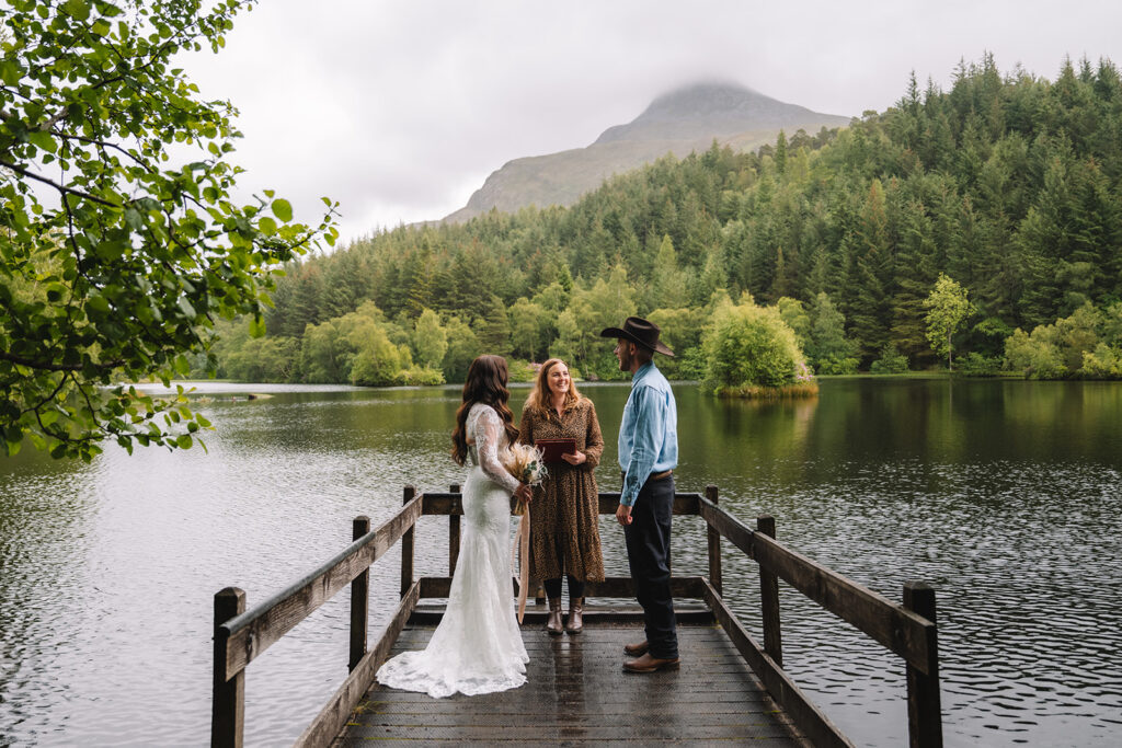 Wedding ceremony taking place on wooden dock over lake.