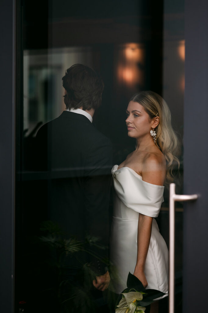 Bride looking at groom through doorway during intimate moment.