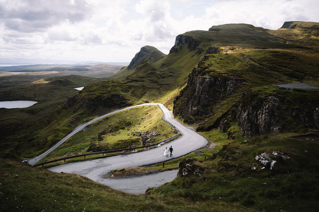 Winding road cutting through green mountainous valley landscape.