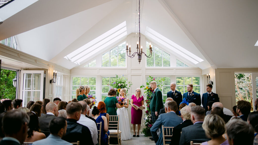 Indoor ceremony in bright venue with guests seated.