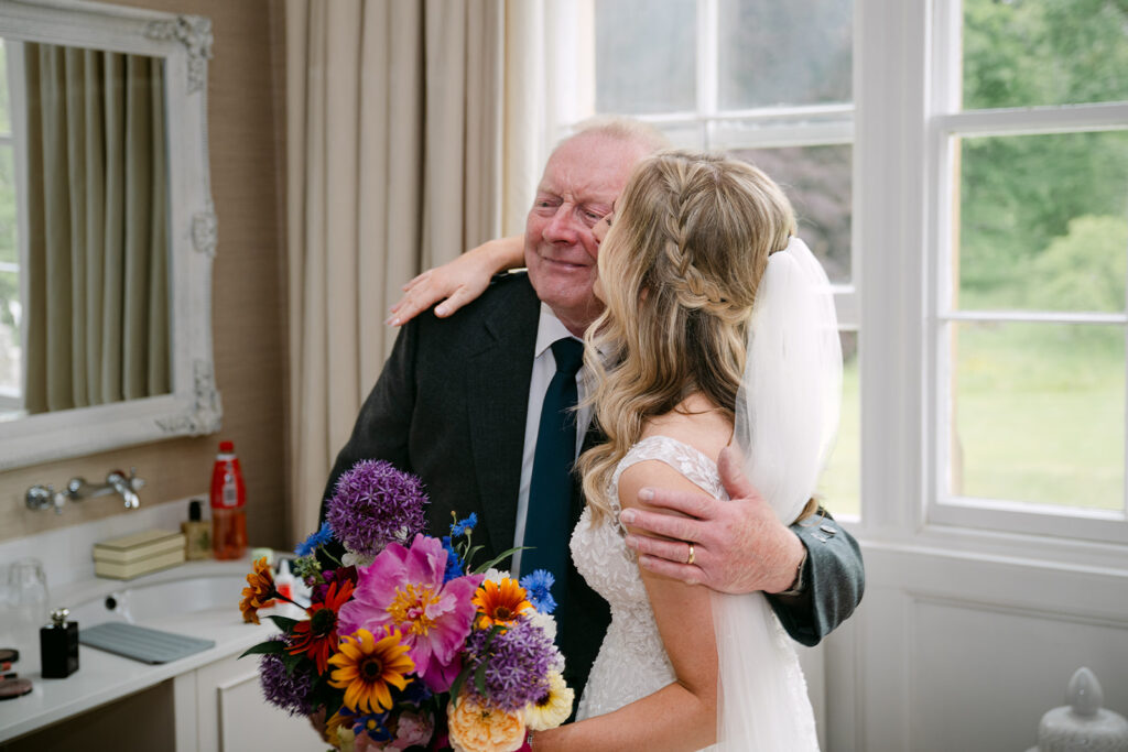 Bride hugging older guest during emotional wedding moment.