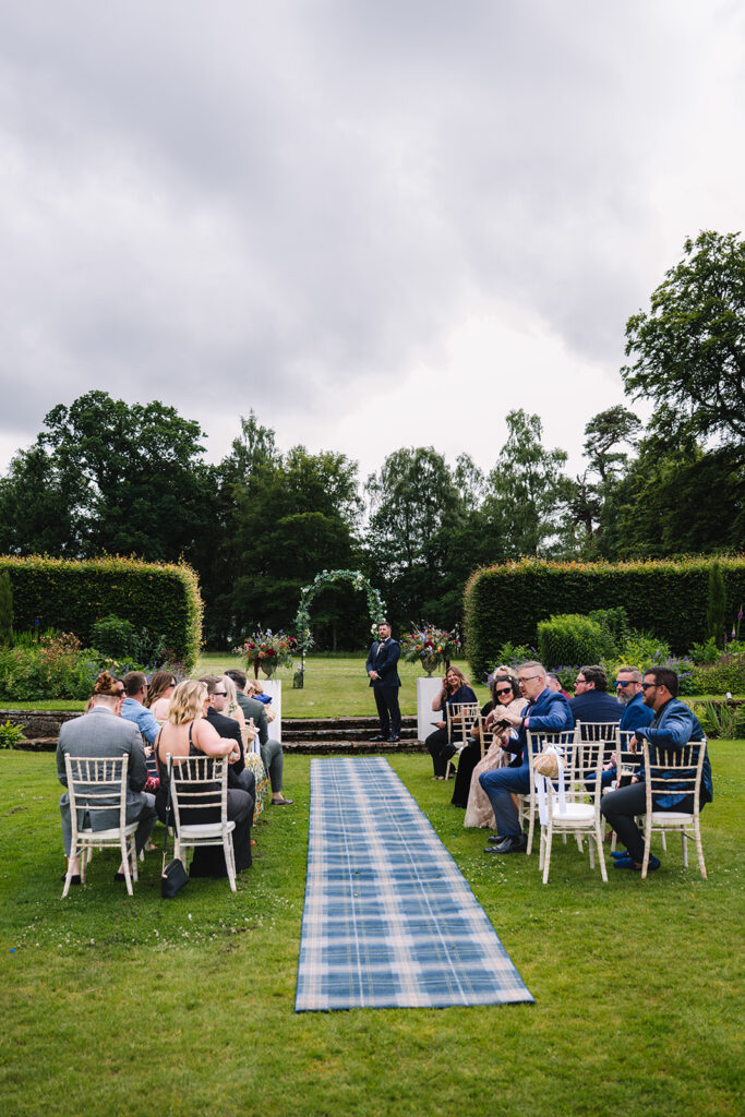 Wide view of outdoor ceremony setup with guests seated.