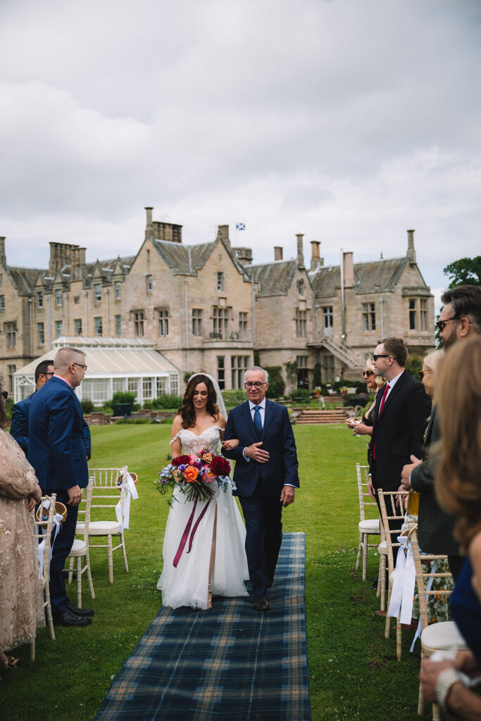 Couple standing with guests during ceremony on lawn.