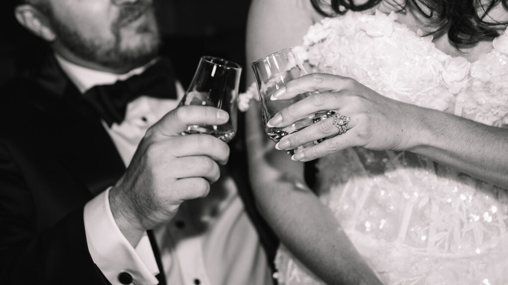 Black and white close-up of couple toasting champagne.