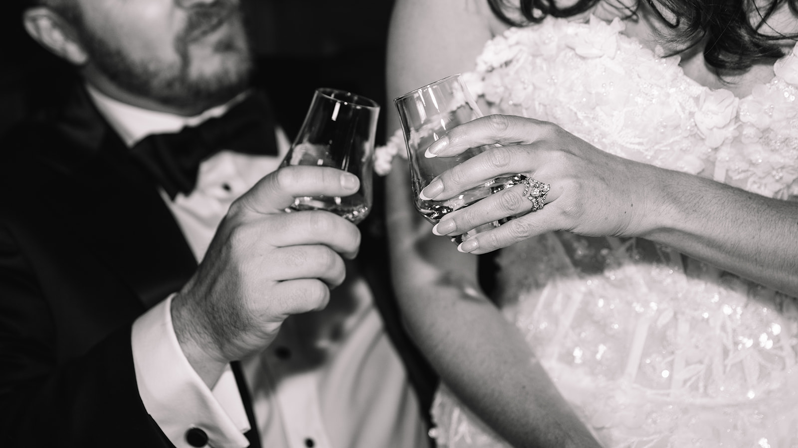 Black and white close-up of couple toasting champagne.