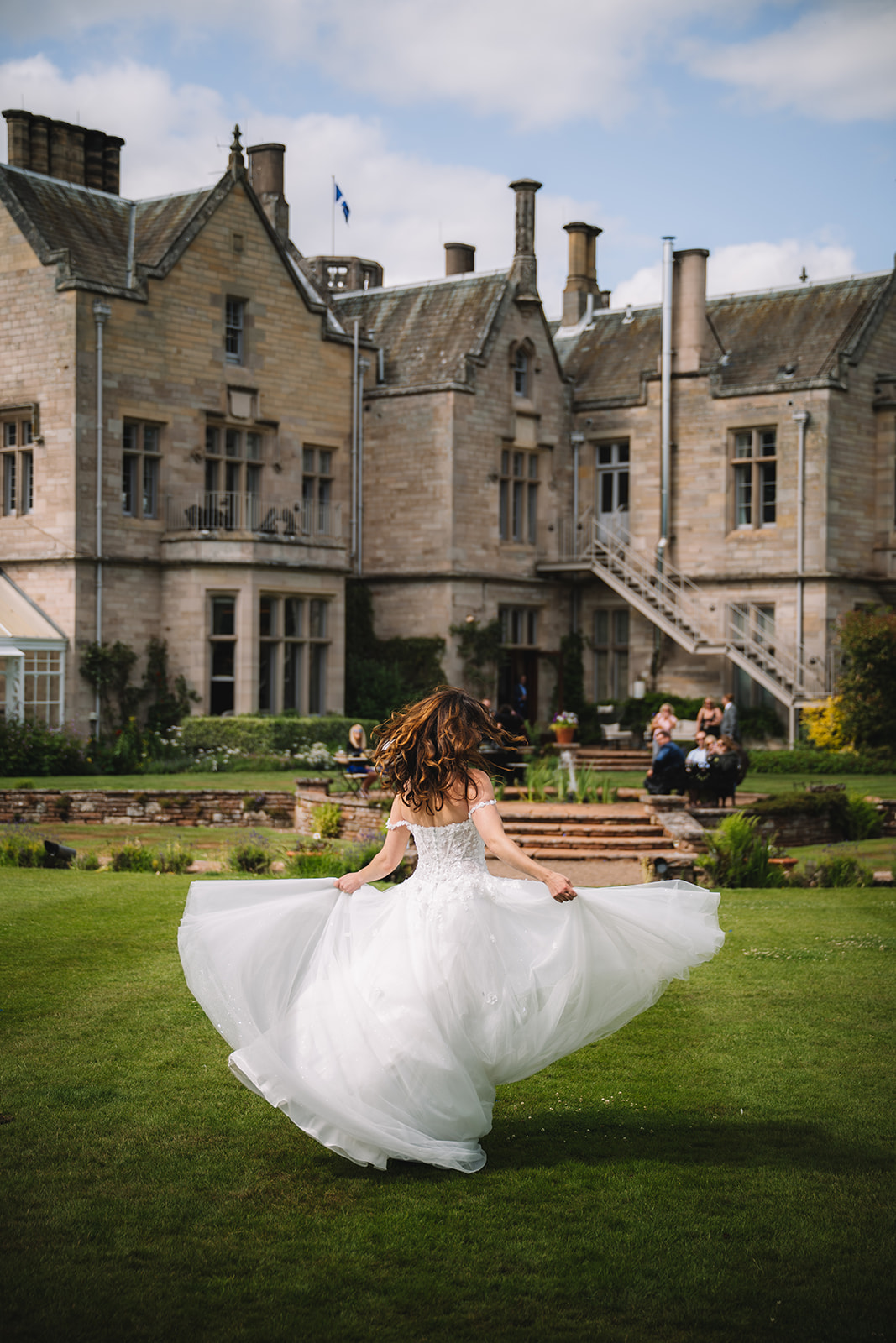 Bride spinning in dress on lawn in front of estate.