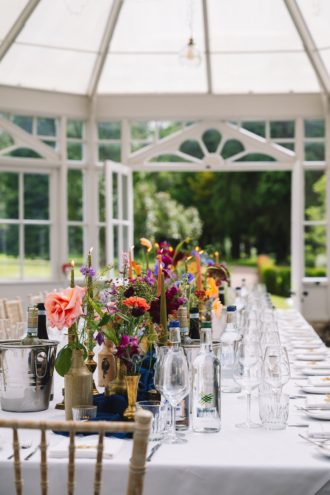 Reception table with colorful floral centerpieces and glassware.