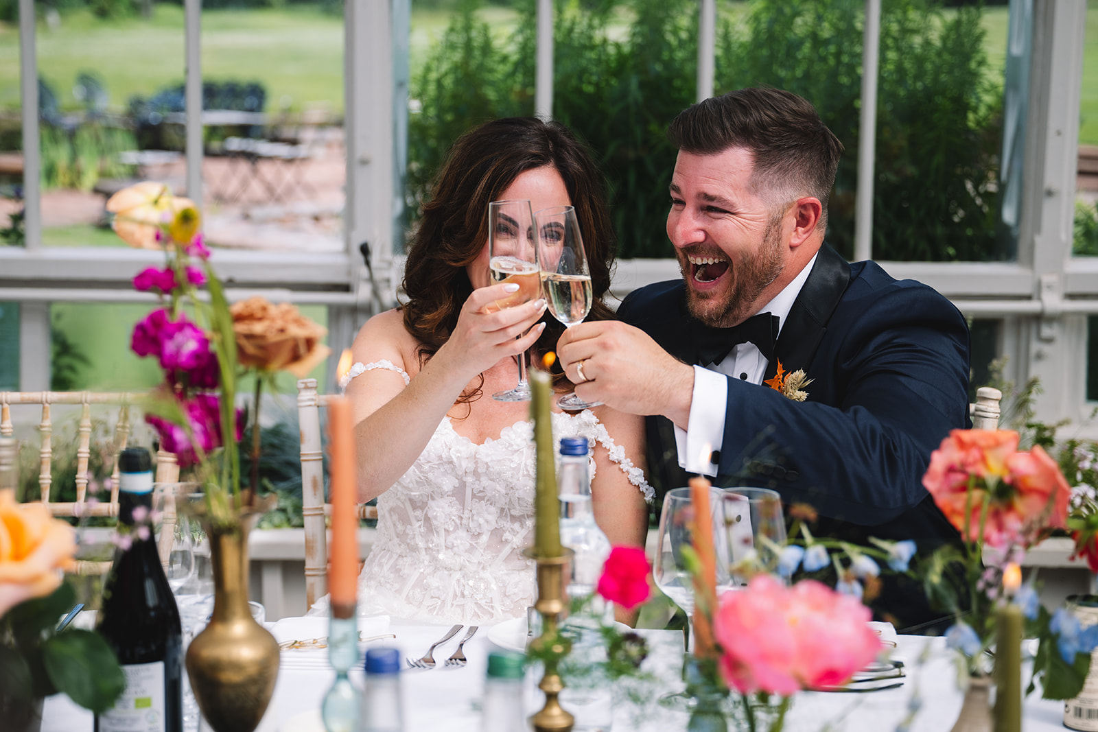 Couple laughing together during reception dinner toast.
