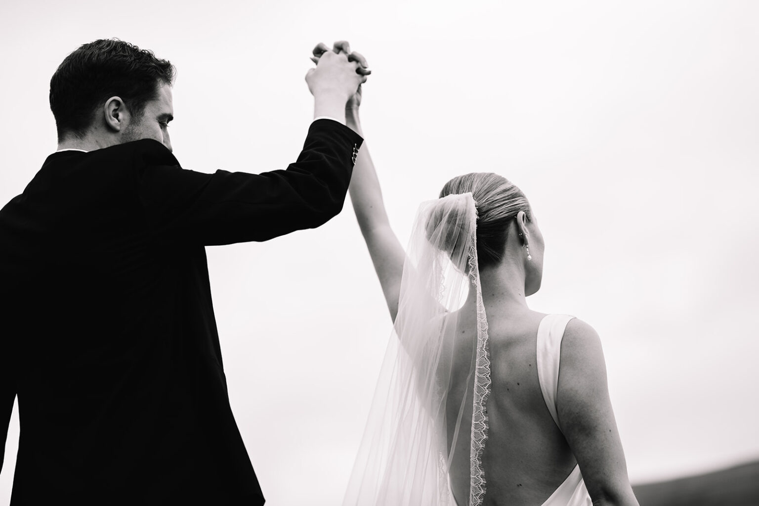Groom twirling bride with raised arm during celebration.