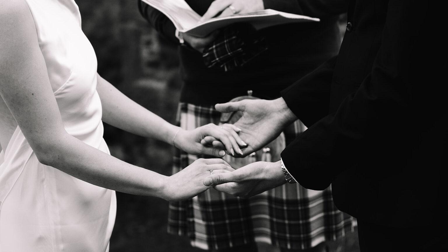Close-up of hands during wedding ceremony in black and white.